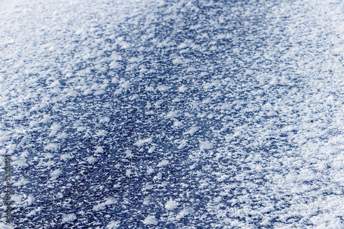 Big fluffy snowflakes on the surface of the ice. Winter and Christmas background