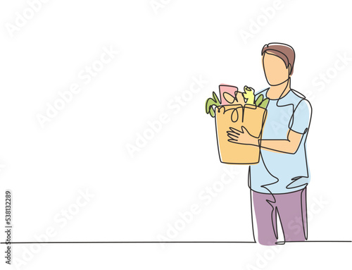 Single continuous line drawing young happy attractive man holding groceries bag full of daily needs. Buying organic product at grocery store concept. One line draw vector graphic design illustration