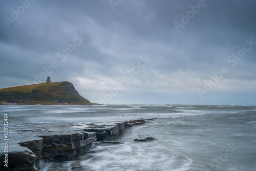 Fading light over the rocky beach of Kimmeridge Bay on the south coast of England, on a cloudy day.  Clavell Tower can be seen on the headland. Room for copy photo