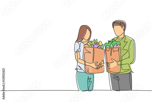 Single continuous line drawing young happy couple holding grocery paper bag after shopping at grocery store together. Buying daily goods concept. One line draw vector graphic design illustration