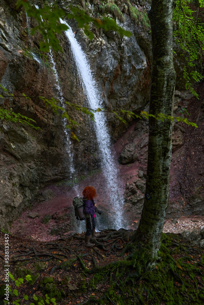Woman nature photographer with camera by a waterfall