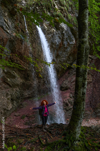 Woman nature photographer with camera by a waterfall
