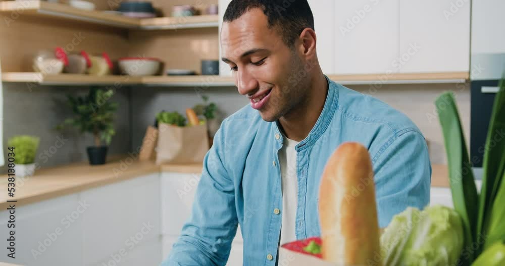 Close-up. Portrait of smiling african-american man using laptop typing at home in kitchen. Man freelance worker. People and technology concept. Close-up. Portrait of smiling african-american man using laptop typing at home in kitchen. Man freelance worker. People and technology concept.