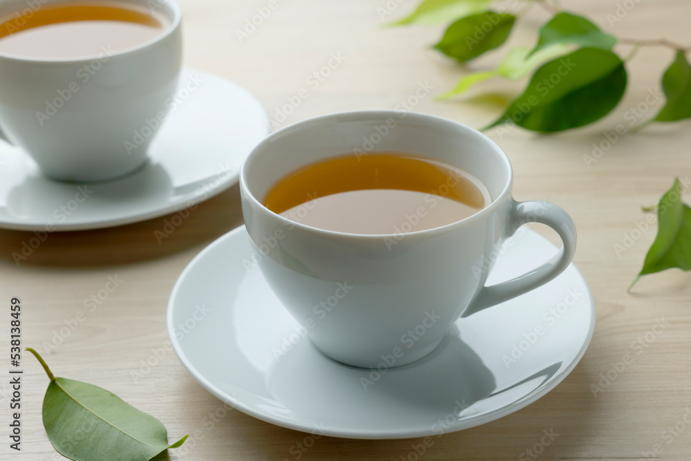 Green tea in white cups with leaves on wooden table, closeup Green tea in white cups with leaves on wooden table, closeup