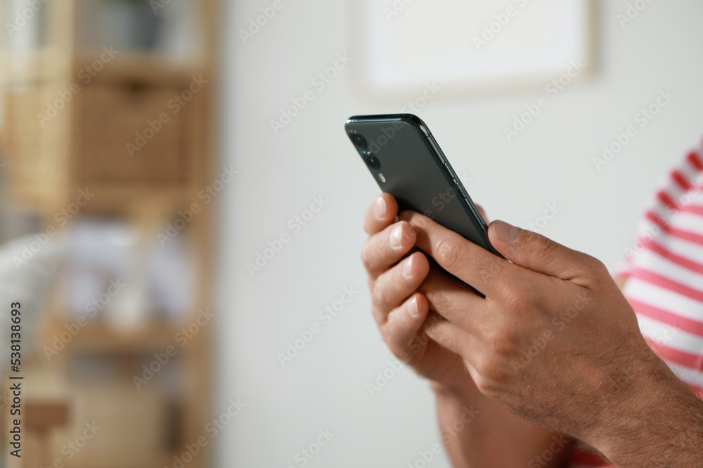 Man using smartphone at home, closeup view. Space for text Man using smartphone at home, closeup view. Space for text