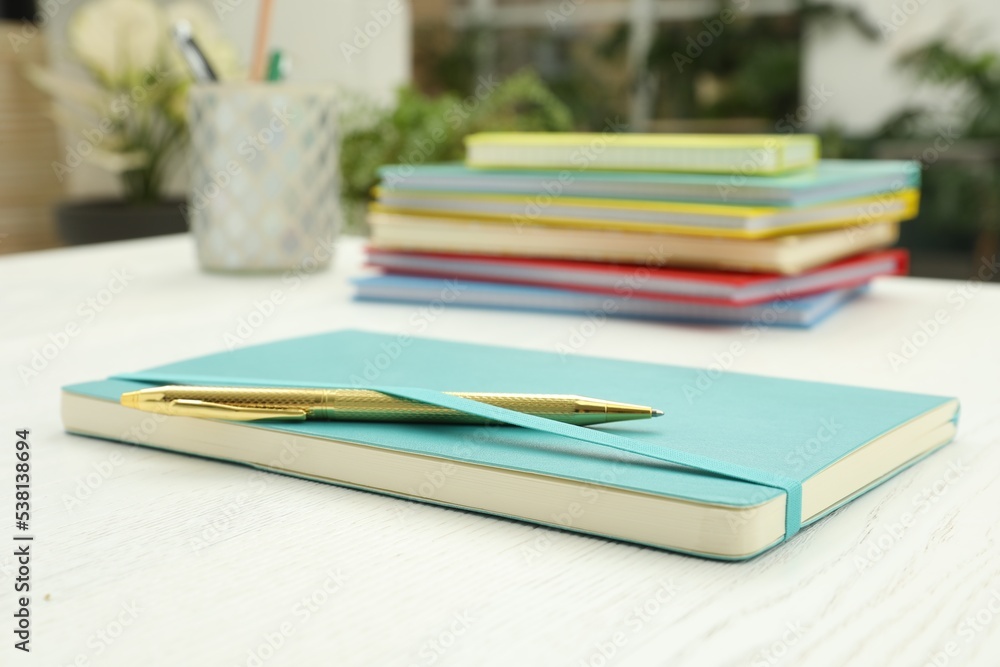 Turquoise planner and pen on white wooden table indoors, closeup Turquoise planner and pen on white wooden table indoors, closeup