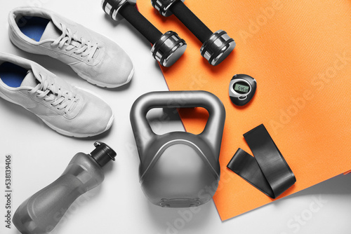 Exercise mat and other sport equipment on white background  flat lay