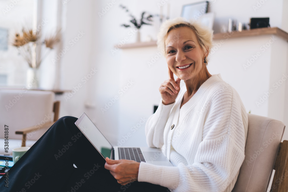 Smiling mature woman with laptop looking at camera Smiling mature woman with laptop looking at camera