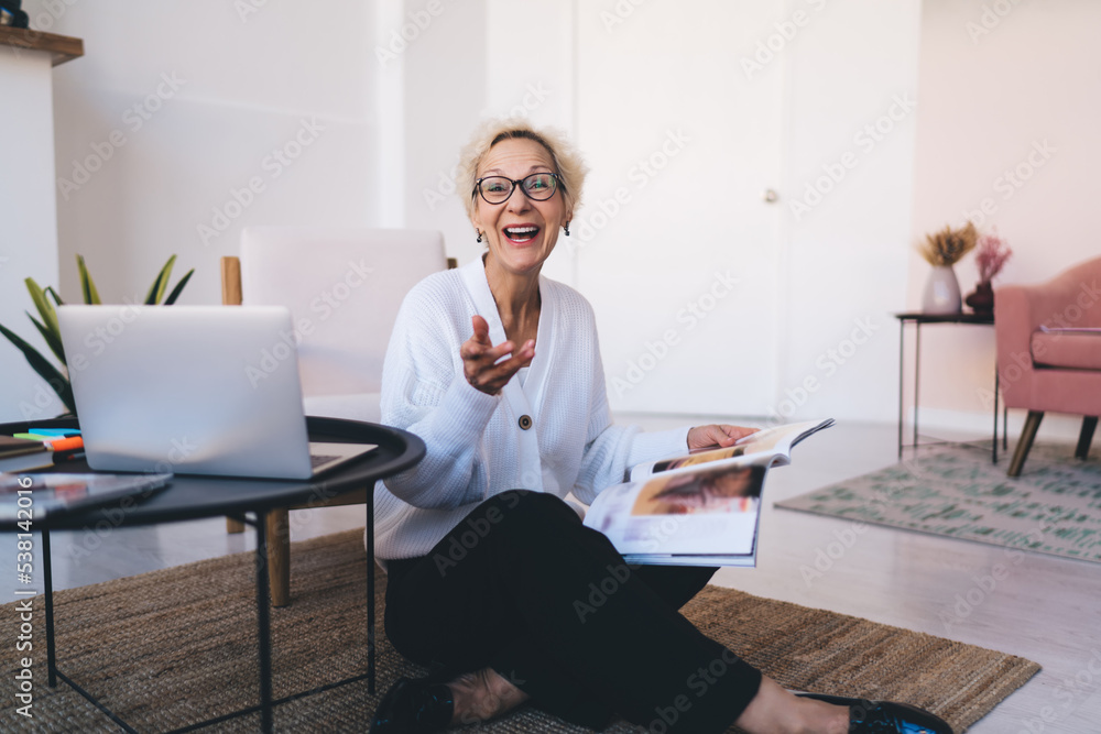 Joyful mature woman with laptop sitting in living room Joyful mature woman with laptop sitting in living room