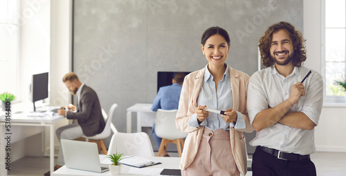 Happy smiling young business people in modern office workplace. Banner background with portrait of two satisfied successful colleagues, team leaders, teammates, business partners and friends at work photo