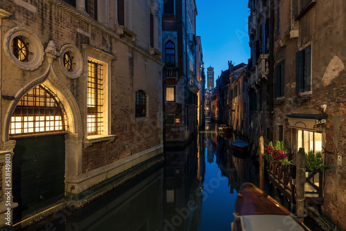 Venetian canal at night time  with the lights of the buildings reflecting in the calm waters
