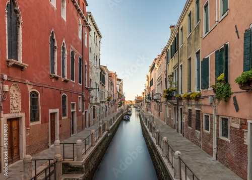 Typical Venetian canal, early in the morning. Venice, Italy. The buildings are reflecting on the calm water © parkerspics