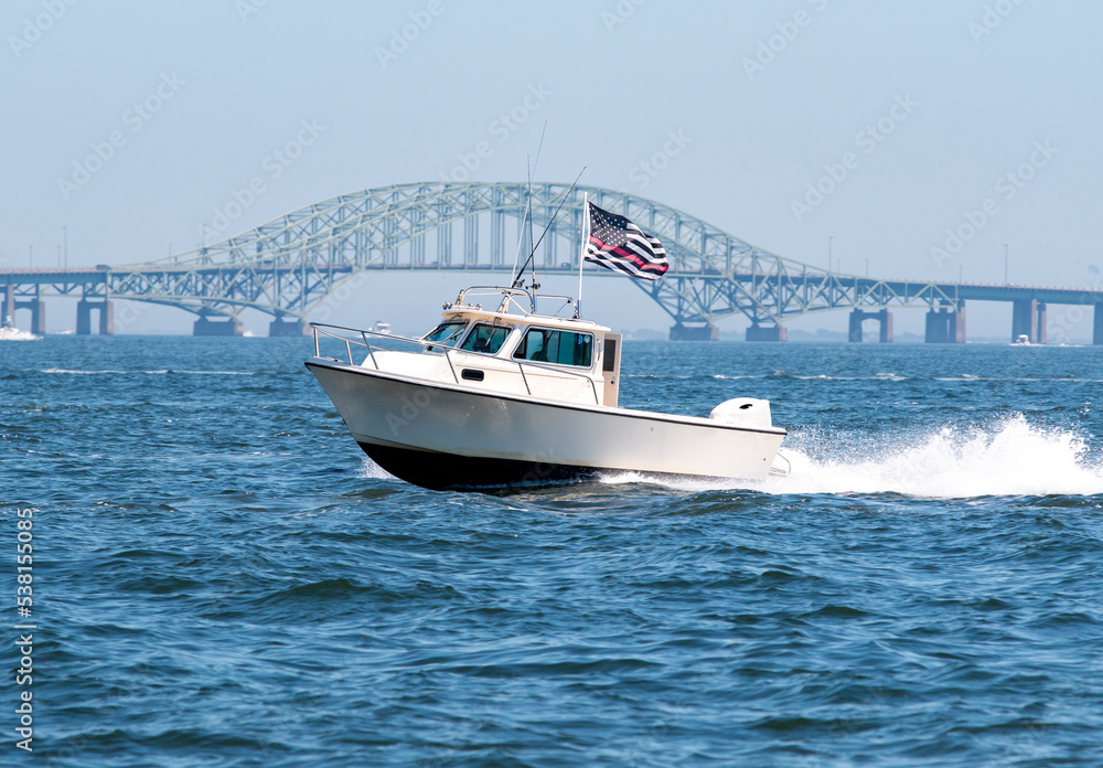 Motor boat with American Flag moving fast with Bridge in background Motor boat with American Flag moving fast with Bridge in background