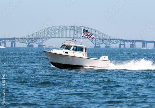 Motor boat with American Flag moving fast with Bridge in background
