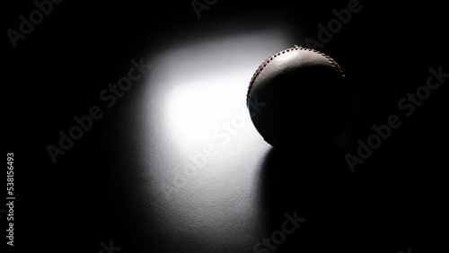White leather baseball poses on black background.