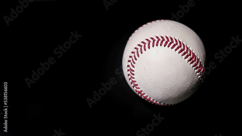 White leather baseball poses on black background.