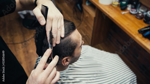 High angle view of hairdresser cutting hair of client in barbershop.