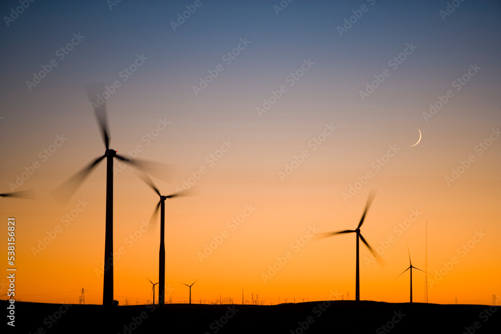 Crescent Moon and wind turbine silhouettes at sunset