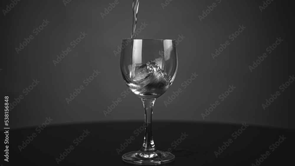 Pour pure drinking water into a glass. a glass with water set on a gray background. Pour pure drinking water into a glass. a glass with water set on a gray background.