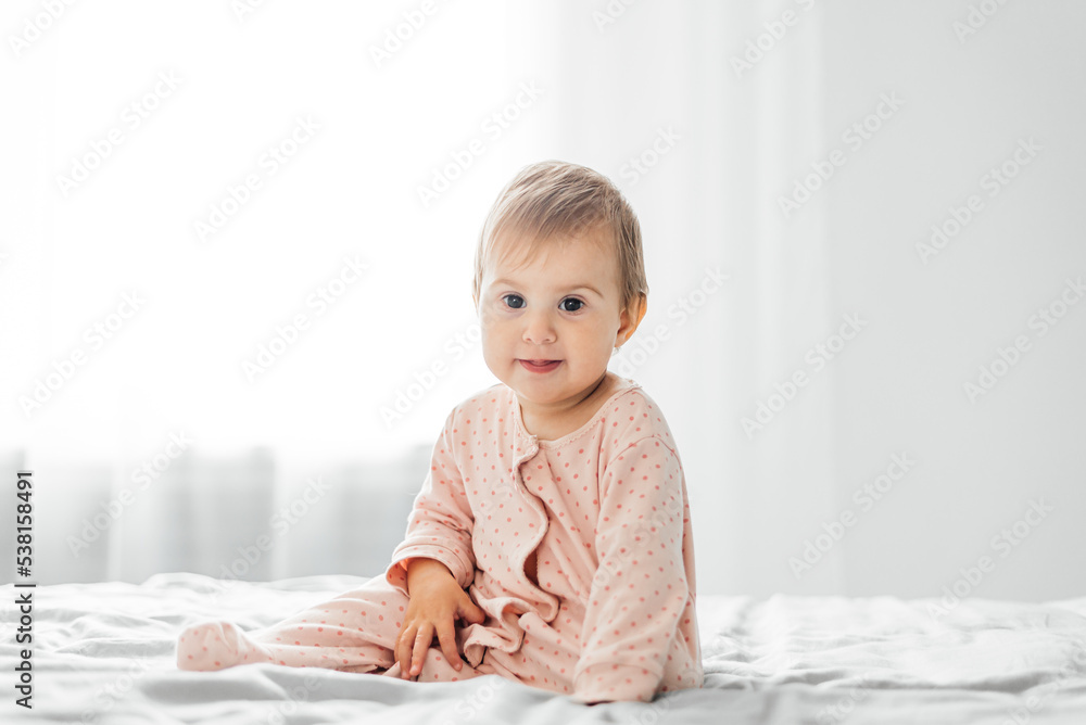 Little baby girl in pink pajamas on the bed Little baby girl in pink pajamas on the bed