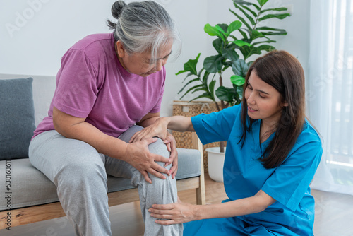 Physical therapist Asian woman, doing leg physiotherapy for elderly woman, to treat osteoarthritis and nerve pain in the leg, to nursing home and health care concept. photo