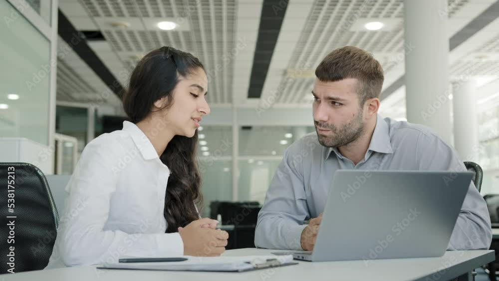 Two colleagues man and woman business people talk in office discussing project looking at laptop screen making presentation satisfied with result negotiations sign successful contract giving high five Two colleagues man and woman business people talk in office discussing project looking at laptop screen making presentation satisfied with result negotiations sign successful contract giving high five