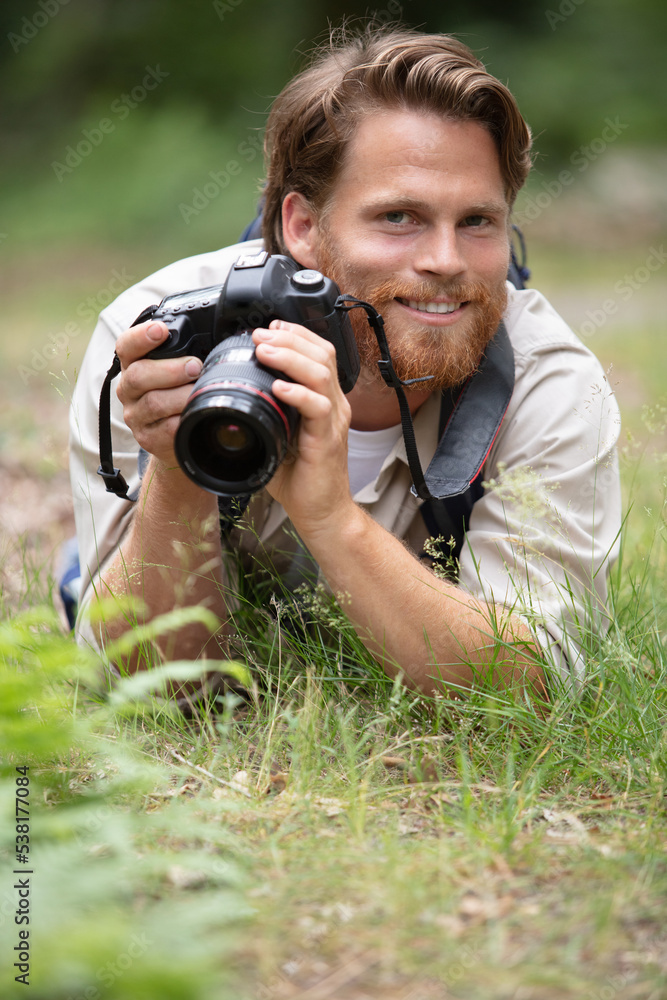 nature photographer lying on grass with camera nature photographer lying on grass with camera