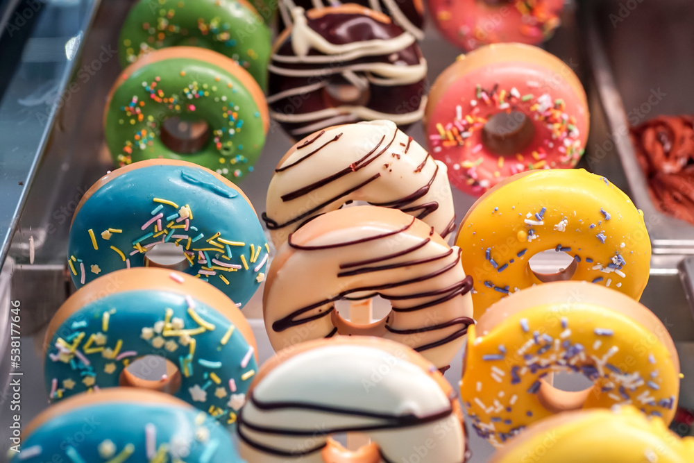 assorted donuts with chocolate frosted, light blue, yellow glazed and sprinkles donuts. carnival concept with sugar.                            