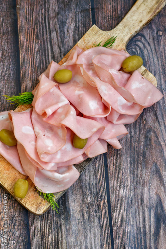 Slices Of Traditional Italian antipasti mortadella Bolognese on a wooden cutting board