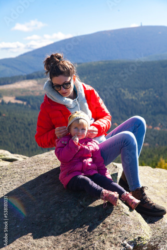 Parent and child in the mountains. Mother with baby on the rock