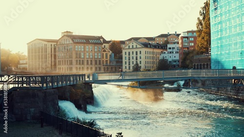 Norrkoping, Sweden. A woman crosses the Tullhusbron bridge during sunset, Steel Construction Award. Classical architecture in the industrial center. Stunning view of Motala ström river.