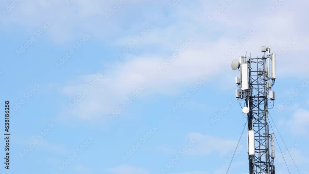 Cell site antenna on a blue sky and white clouds background. Place for text. Cell tower with mobile Telecommunications equipment. Cellular tower base station with electronic communications equipment Cell site antenna on a blue sky and white clouds background. Place for text. Cell tower with mobile Telecommunications equipment. Cellular tower base station with electronic communications equipment