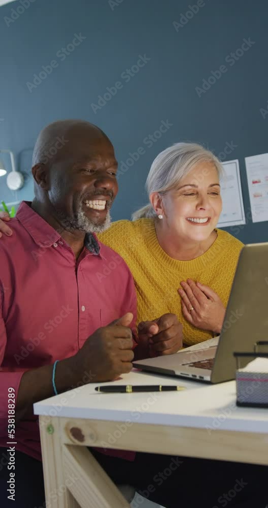 Vertical video of happy diverse senior couple making video call on laptop together at home waving Vertical video of happy diverse senior couple making video call on laptop together at home waving