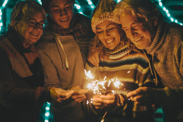 Family enjoying and having fun in christmas and new year celebration. Group of adult young and senior people celebrate together with sparklers light. Menand women in friendship in holiday season
