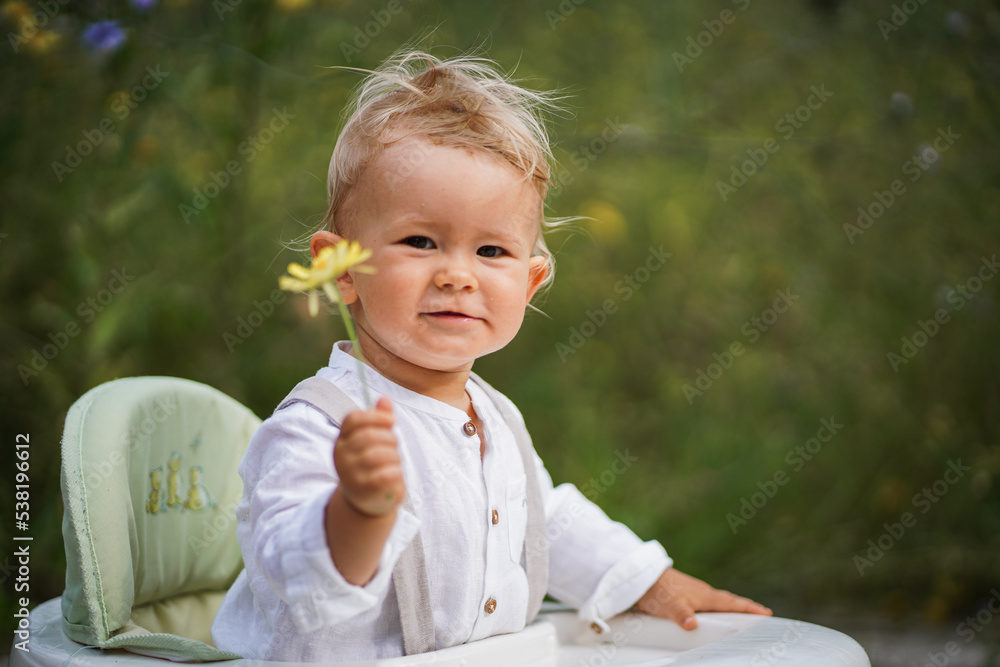 one year old happy blond german baby boy in white shirt playing outside in the garden with a yellow flower to send love or congratulate for birthday
one year old happy blond german baby boy in white shirt playing outside in the garden with a yellow flower to send love or congratulate for birthday