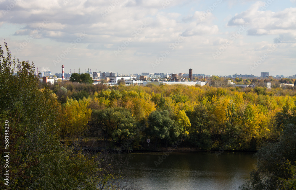 Panoramic top view of the city of Moscow with buildings among the lush foliage of autumn trees and the river on a sunny cloudy October day