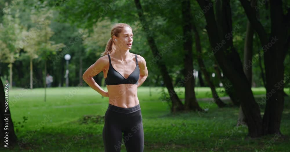 Woman in sportswear stretching body before a workout in the park Woman in sportswear stretching body before a workout in the park
