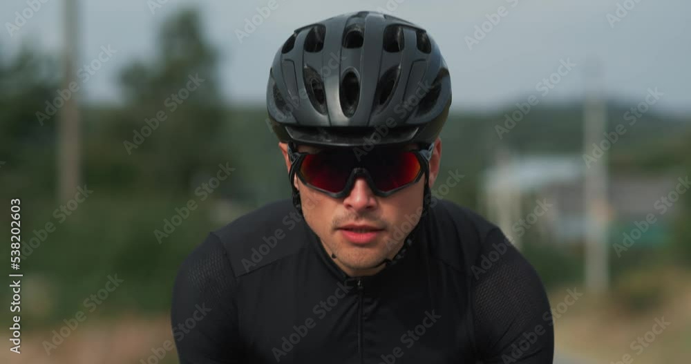 Portrait of man cyclist in helmet riding on a bicycle on road in the countryside Portrait of man cyclist in helmet riding on a bicycle on road in the countryside