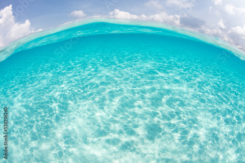 Bright sunlight reflects off of white sand in the clear  warm seas of the tropical Pacific. 