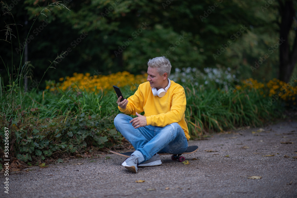 A woman sits on a skateboard and looks into her phone and does salfy A woman sits on a skateboard and looks into her phone and does salfy