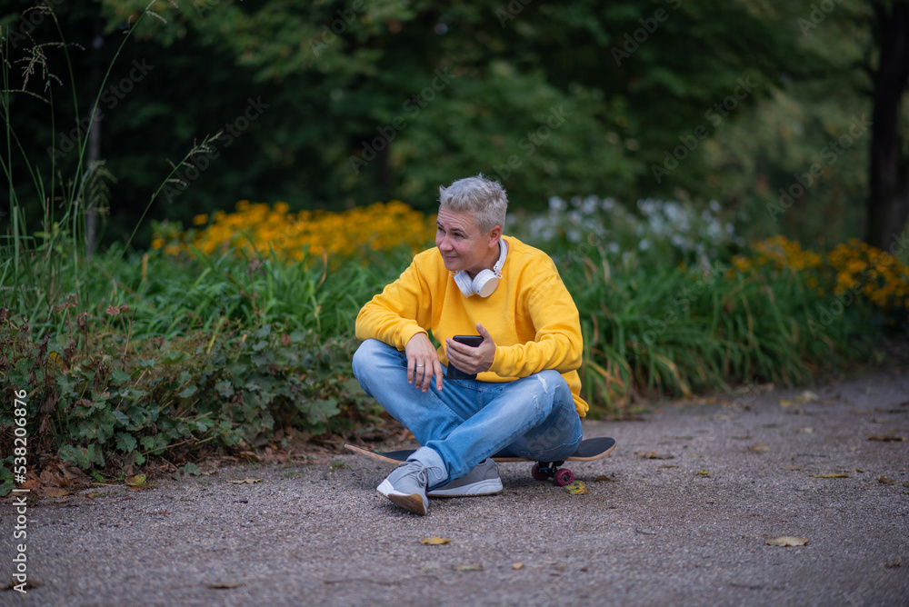 Obraz premium A woman sits on a skateboard and looks into her phone and does salfy
