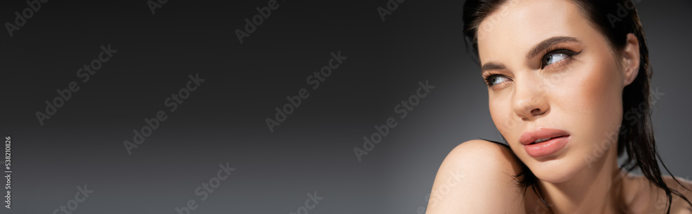 Young model with naked shoulders looking away isolated on grey, banner.