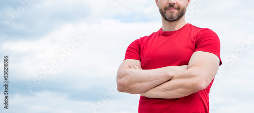 cropped view of man in red shirt crossed hands on sky background. copy space