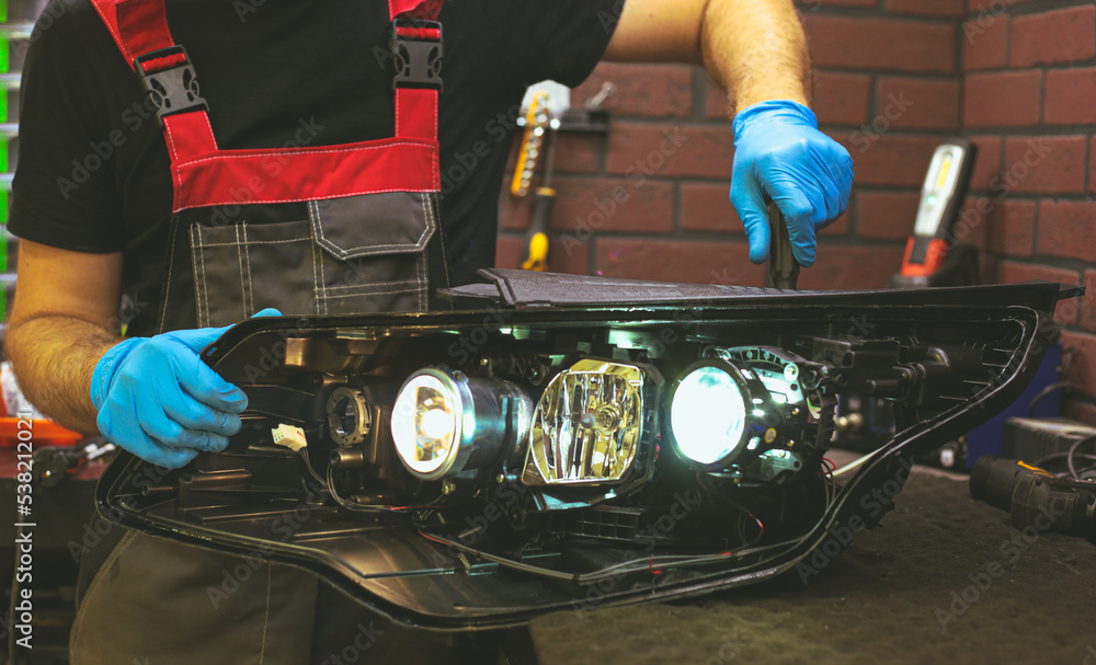 Car headlight in repair closeup. The car mechanic installs the lens in
