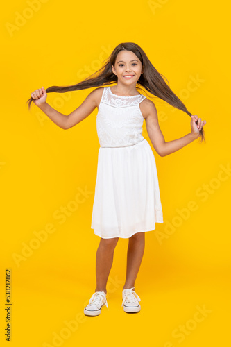 cute teen girl with long hair standing on yellow background