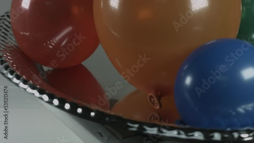 Multicolor Balloons Slowly Rotate on Metallic Platter 4K photo