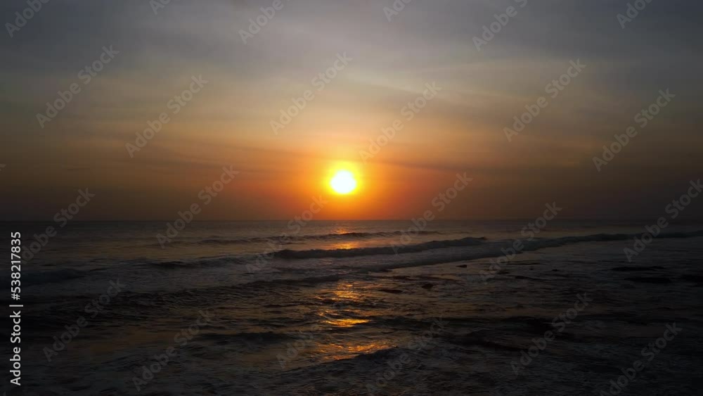 A view from a drone flying over the sea with waves and a view of the fiery sunset above the water A view from a drone flying over the sea with waves and a view of the fiery sunset above the water