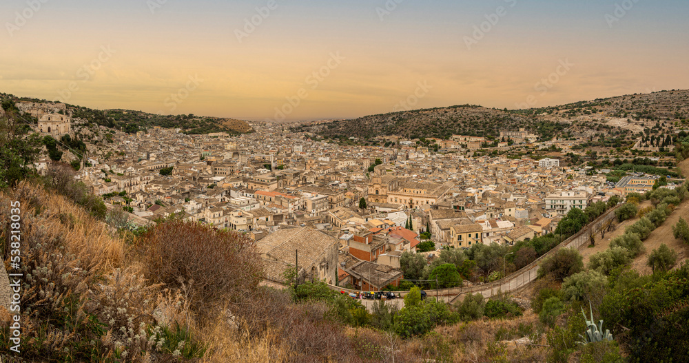 Extra wide aerial landscape of Scicli with beautiful historic buildings in the Baroque style at sunset
