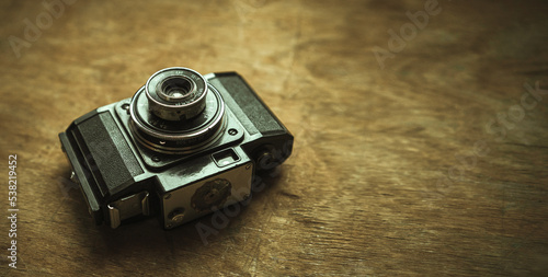 Black vintage film camera on a wooden table in retro style. Shooting analog photography. A plastic camera of the last century.