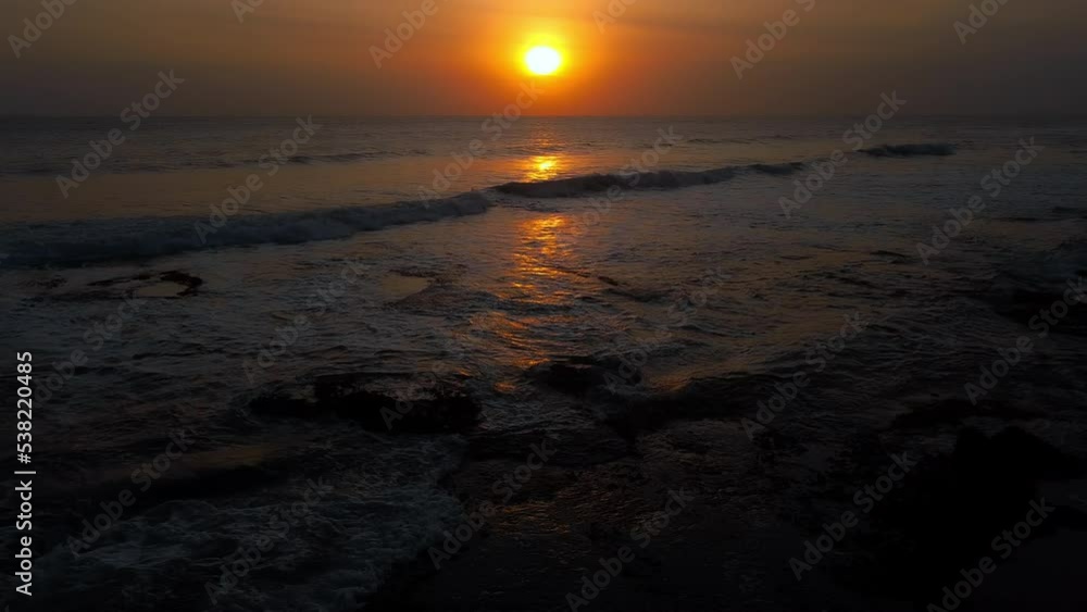 A view from a drone flying over the sea with waves and a view of the fiery sunset above the water A view from a drone flying over the sea with waves and a view of the fiery sunset above the water